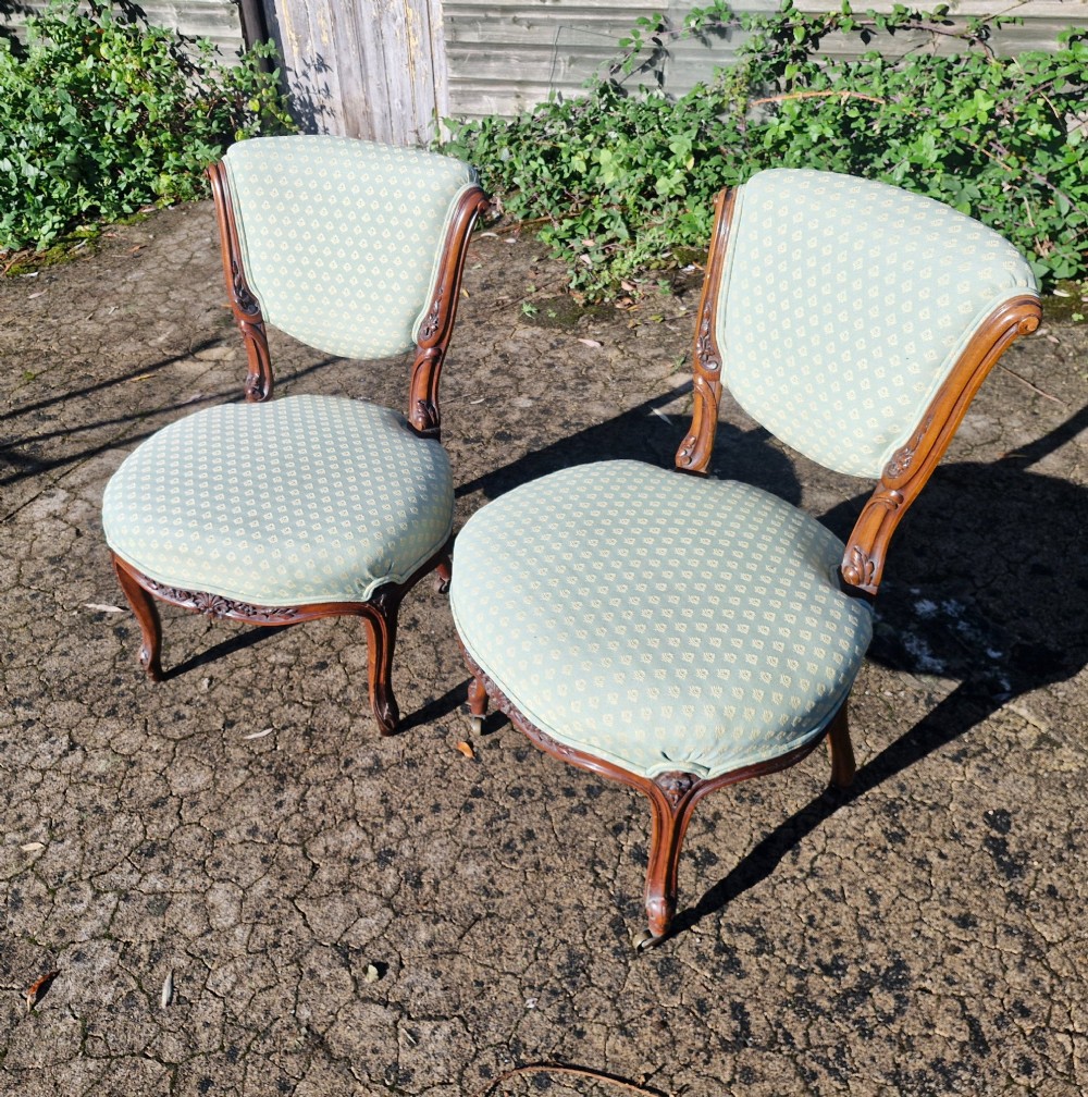 A pair of late Victorian low-seated bedroom chairs with carved walnut frames and light green patterned upholstery. View IV