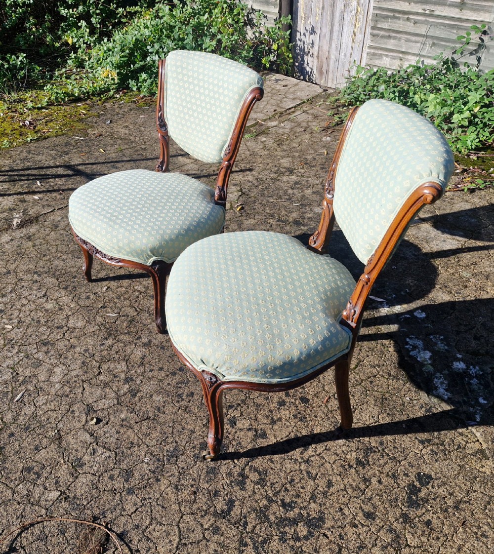 A pair of late Victorian low-seated bedroom chairs with carved walnut frames and light green patterned upholstery. View V