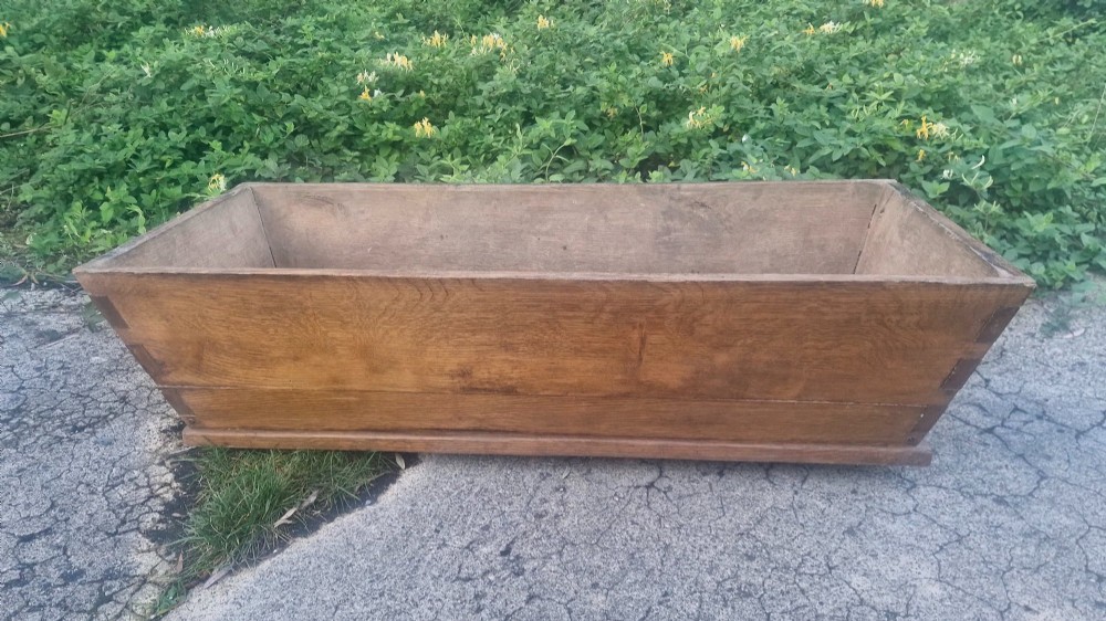 A rectangular open-topped solid oak trough with splayed sides and exposed dovetail joinery. View III