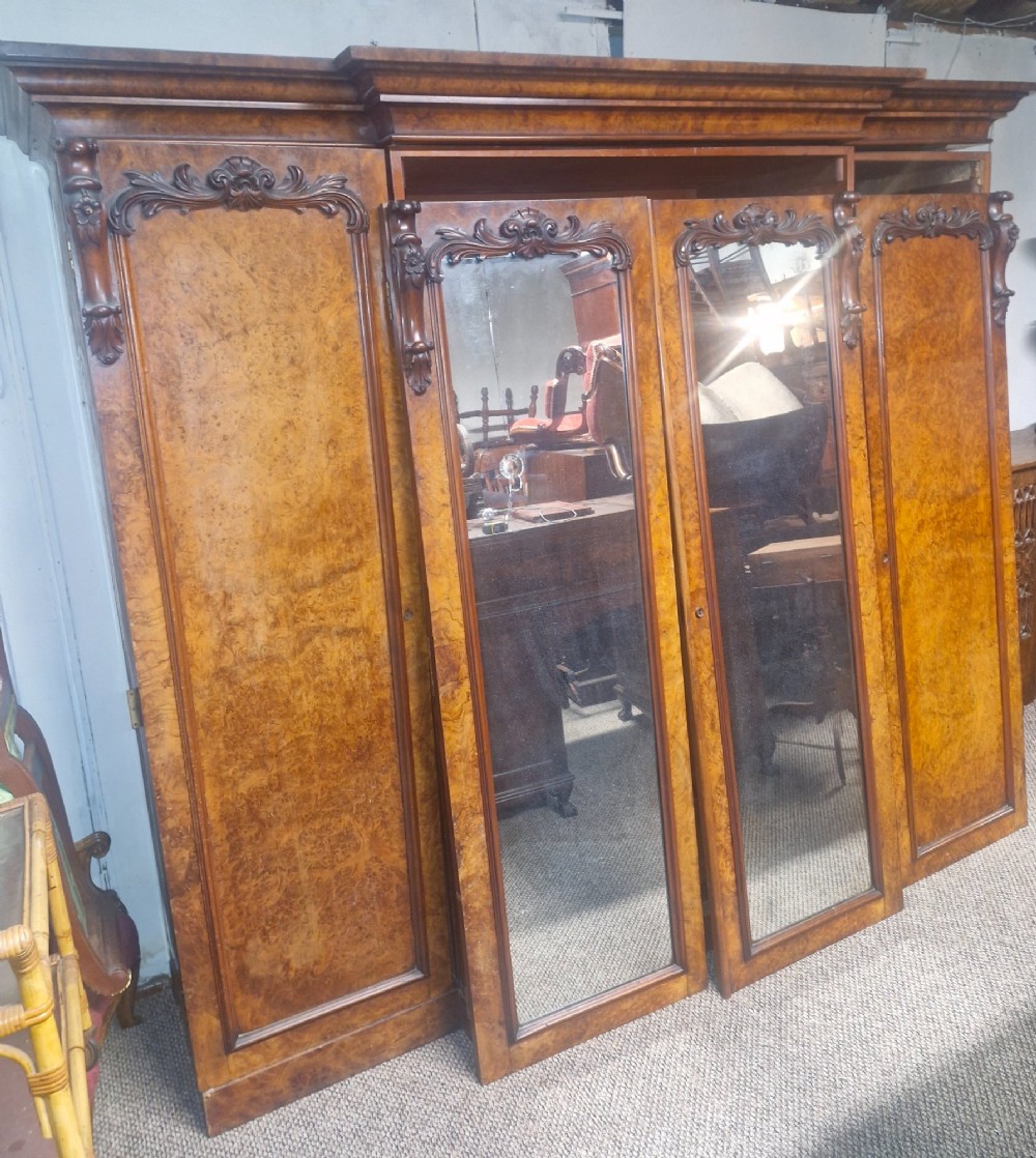 A large Victorian breakfront wardrobe crafted from highly figured burr walnut with two central mirrored doors and carved scrollwork details. View II