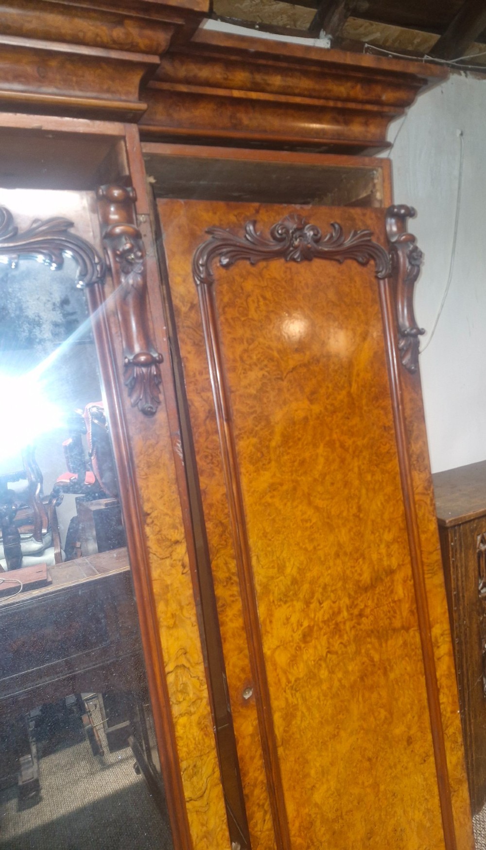 A large Victorian breakfront wardrobe crafted from highly figured burr walnut with two central mirrored doors and carved scrollwork details. View IV