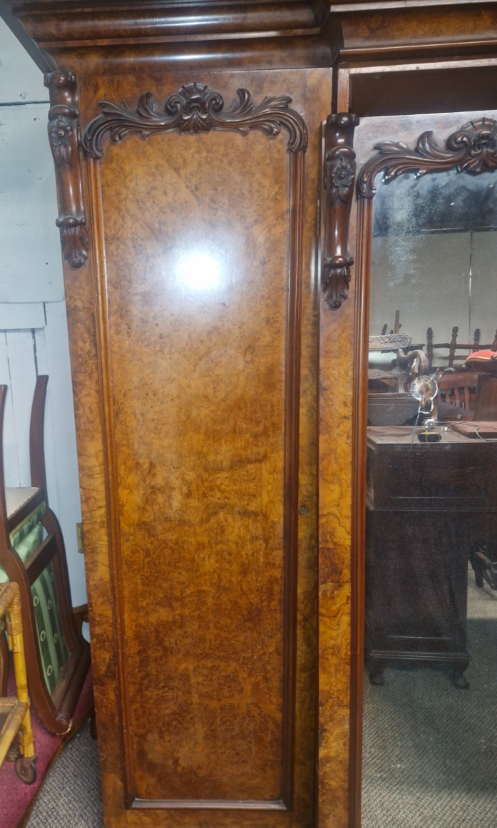 A large Victorian breakfront wardrobe crafted from highly figured burr walnut with two central mirrored doors and carved scrollwork details. View V