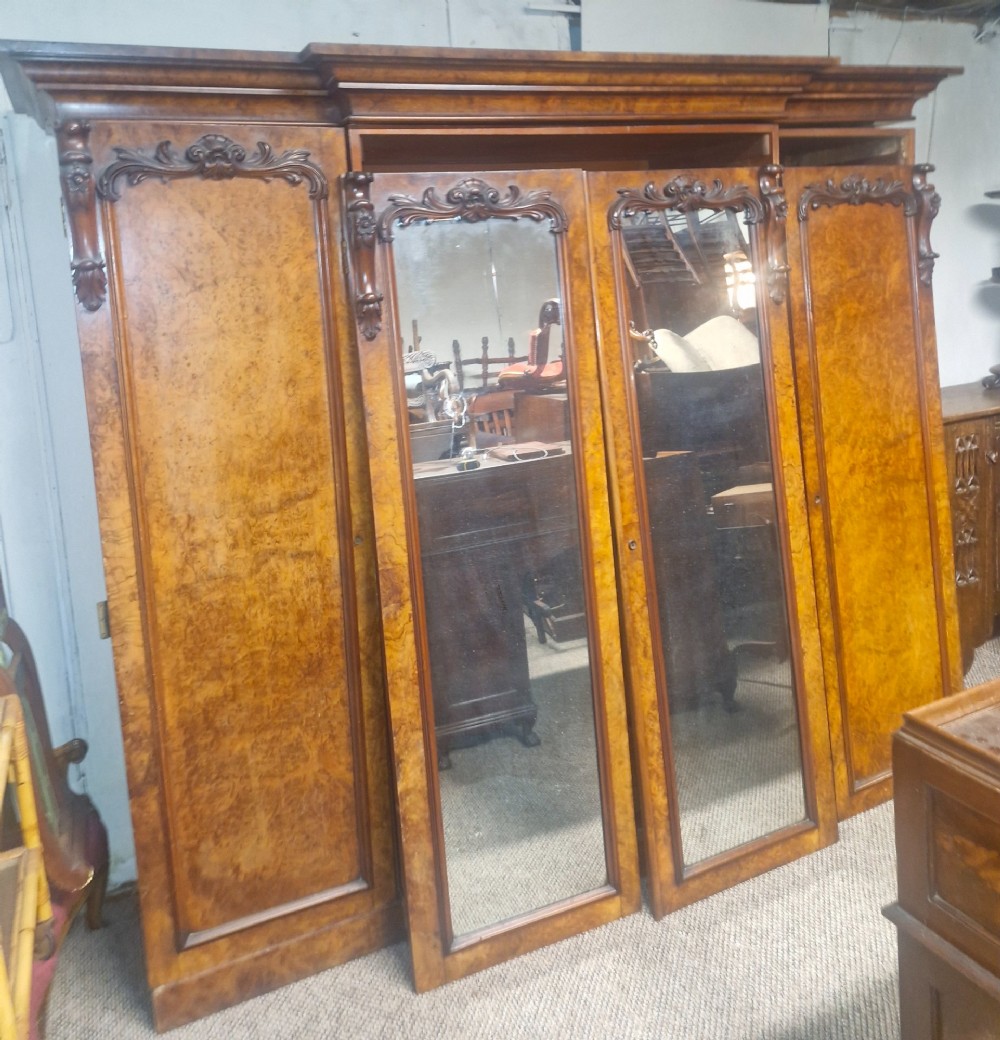 A large Victorian breakfront wardrobe crafted from highly figured burr walnut with two central mirrored doors and carved scrollwork details. View VI