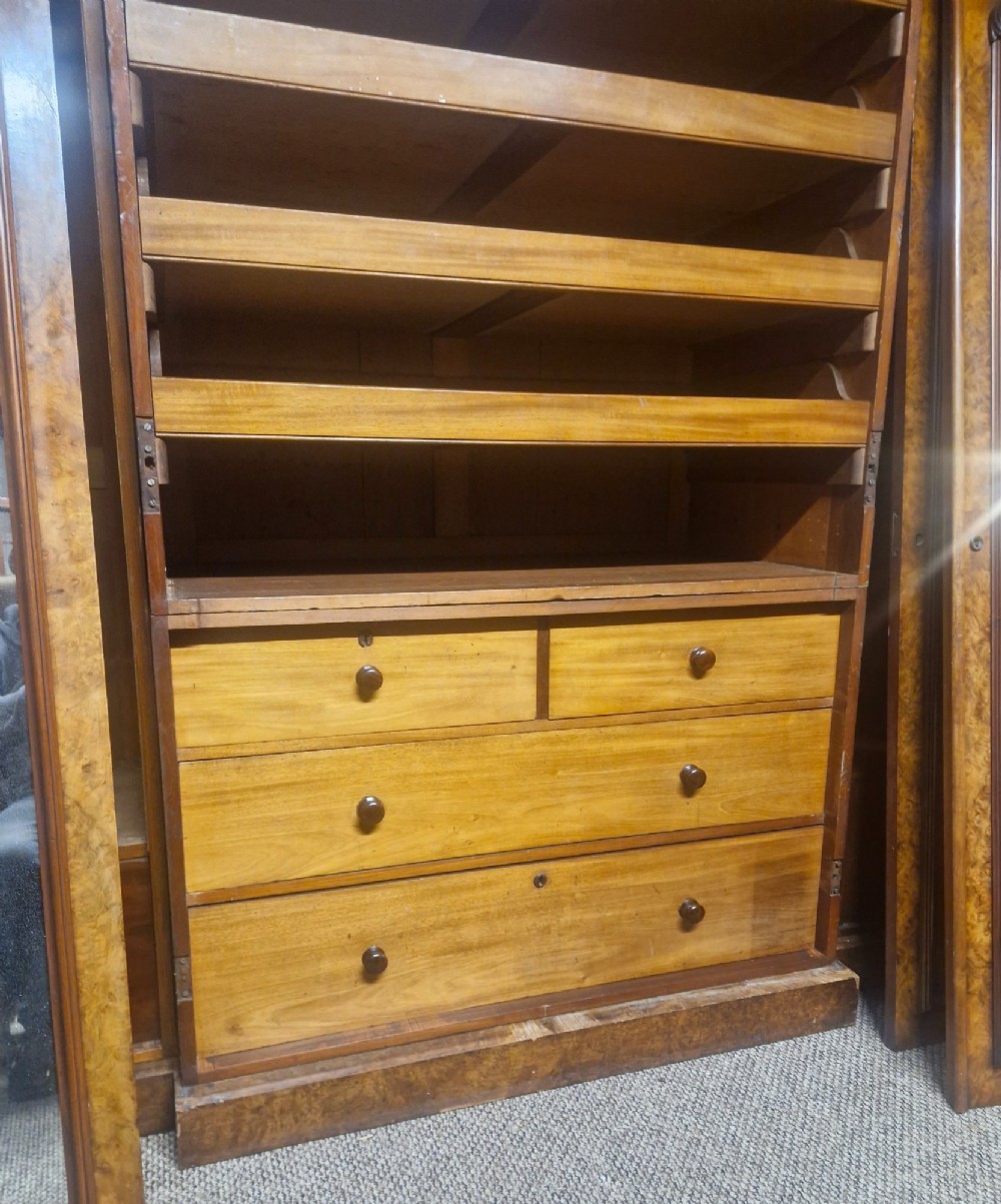 A large Victorian breakfront wardrobe crafted from highly figured burr walnut with two central mirrored doors and carved scrollwork details. View XIII