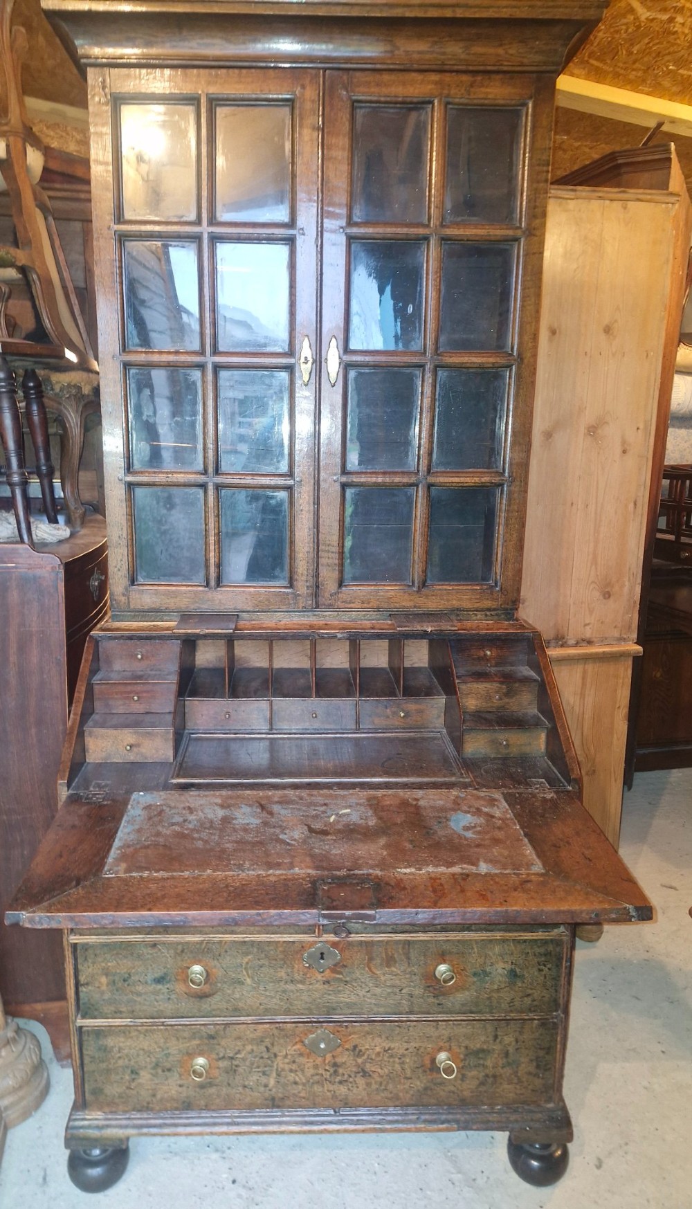An antique oak bureau bookcase featuring a two-door glazed upper section, a slant-front writing desk, candle slides, and lower drawers raised on bun feet. View III