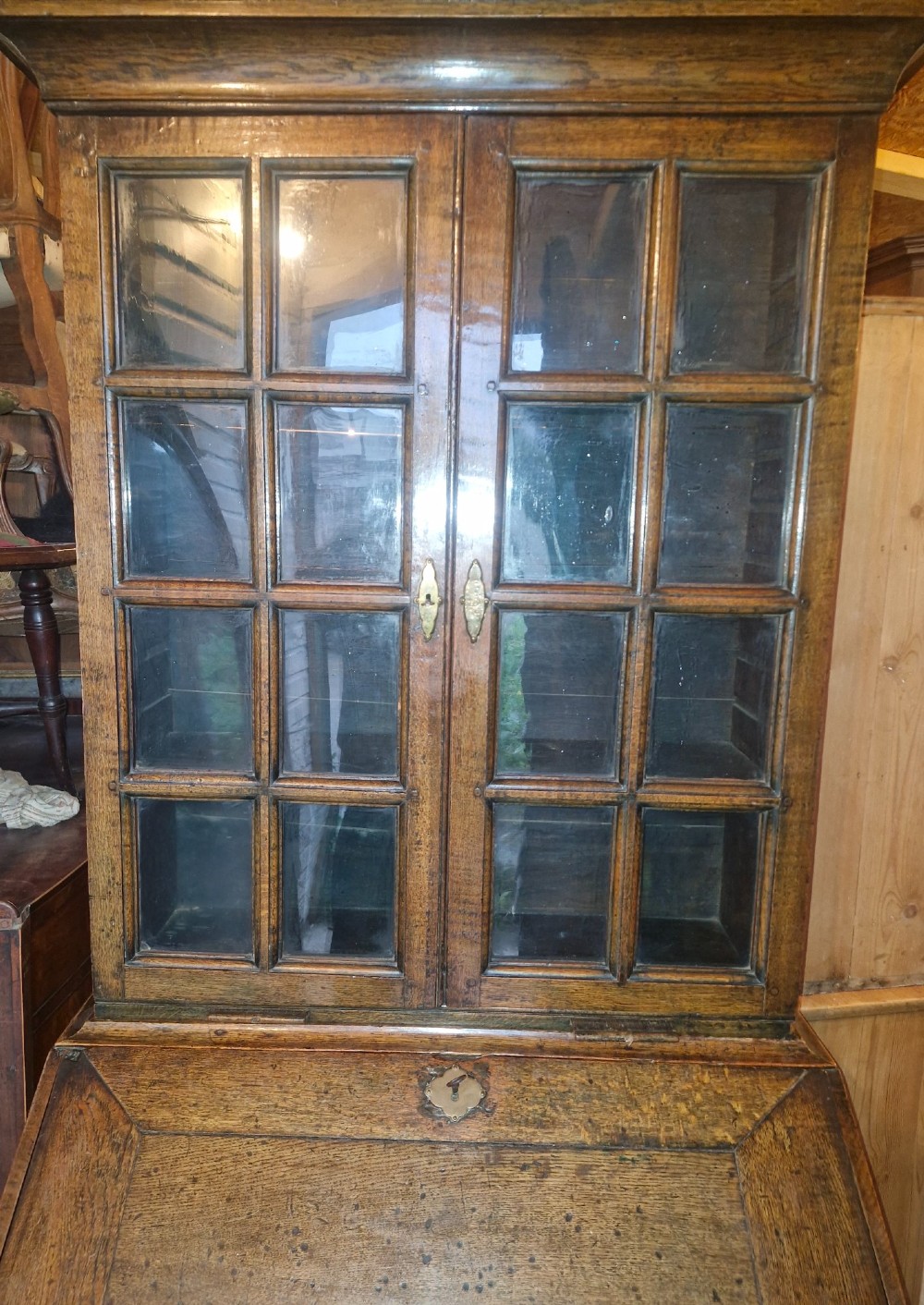 An antique oak bureau bookcase featuring a two-door glazed upper section, a slant-front writing desk, candle slides, and lower drawers raised on bun feet. View XI