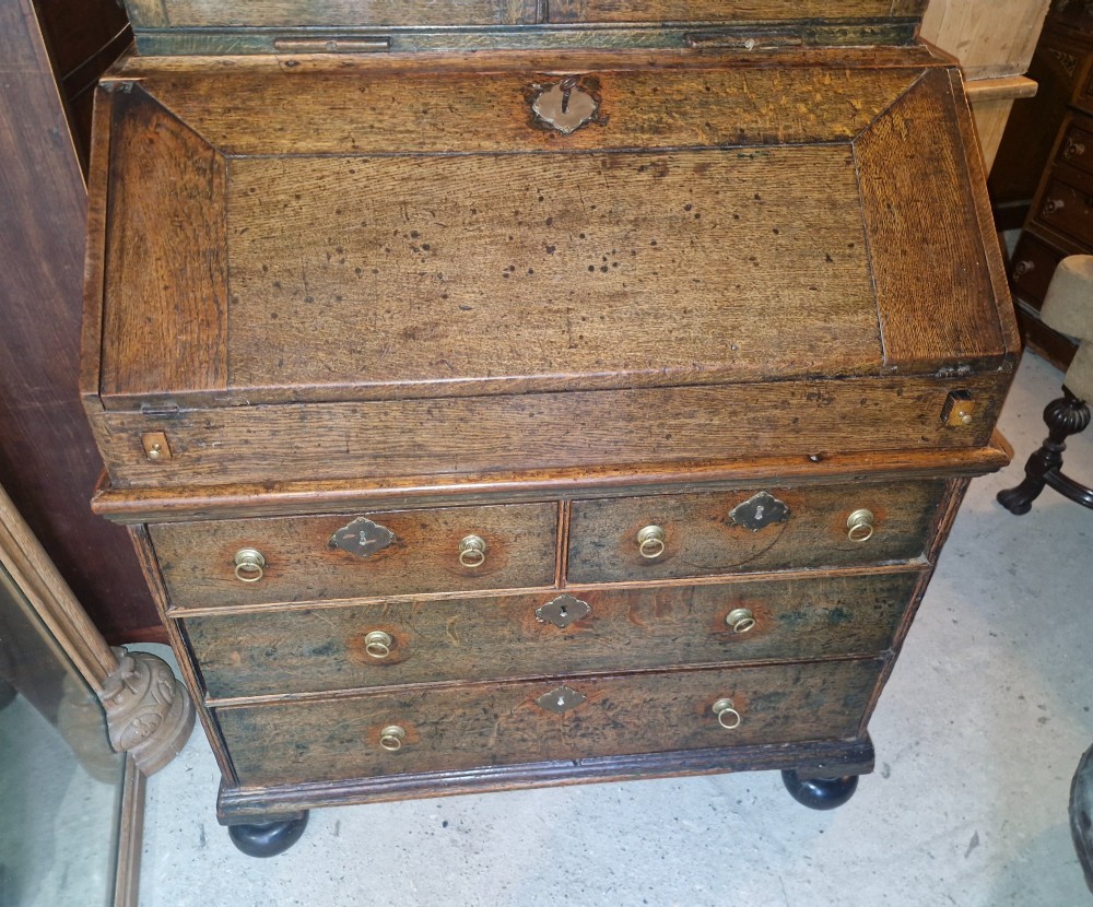 An antique oak bureau bookcase featuring a two-door glazed upper section, a slant-front writing desk, candle slides, and lower drawers raised on bun feet. View XII
