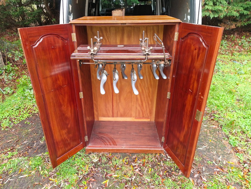 An open twin-door mahogany valet cupboard revealing an internal trouser press mechanism with brass turn-screws and integrated hanging racks. View II