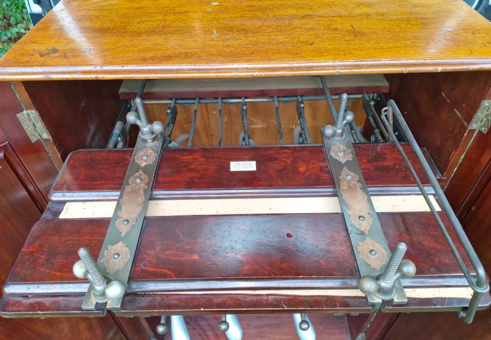 An open twin-door mahogany valet cupboard revealing an internal trouser press mechanism with brass turn-screws and integrated hanging racks. View XI
