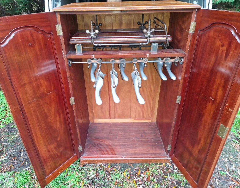 An open twin-door mahogany valet cupboard revealing an internal trouser press mechanism with brass turn-screws and integrated hanging racks. View XIII