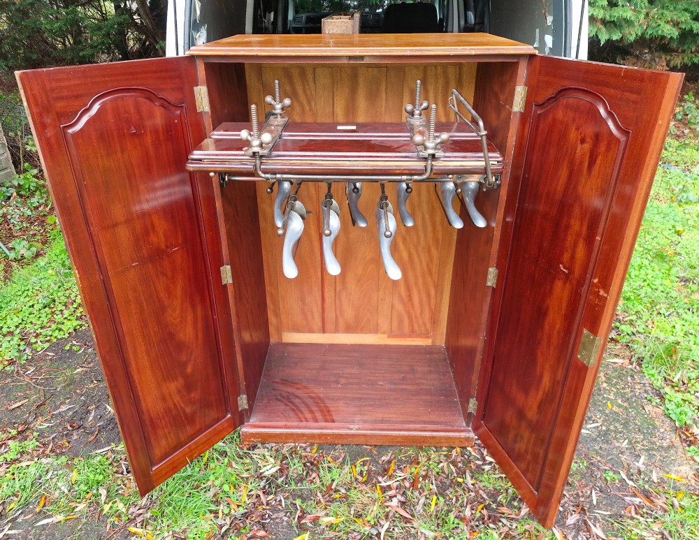 An open twin-door mahogany valet cupboard revealing an internal trouser press mechanism with brass turn-screws and integrated hanging racks. View XIV
