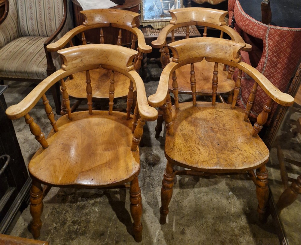 A set of four wooden smokers bow armchairs with continuous curved armrests, turned spindles, shaped seats, and turned legs. View III