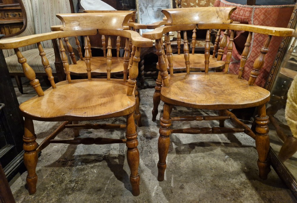 A set of four wooden smokers bow armchairs with continuous curved armrests, turned spindles, shaped seats, and turned legs. View IV