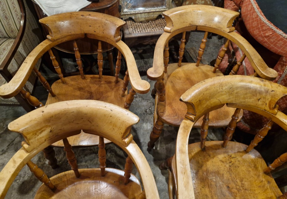 A set of four wooden smokers bow armchairs with continuous curved armrests, turned spindles, shaped seats, and turned legs. View VI