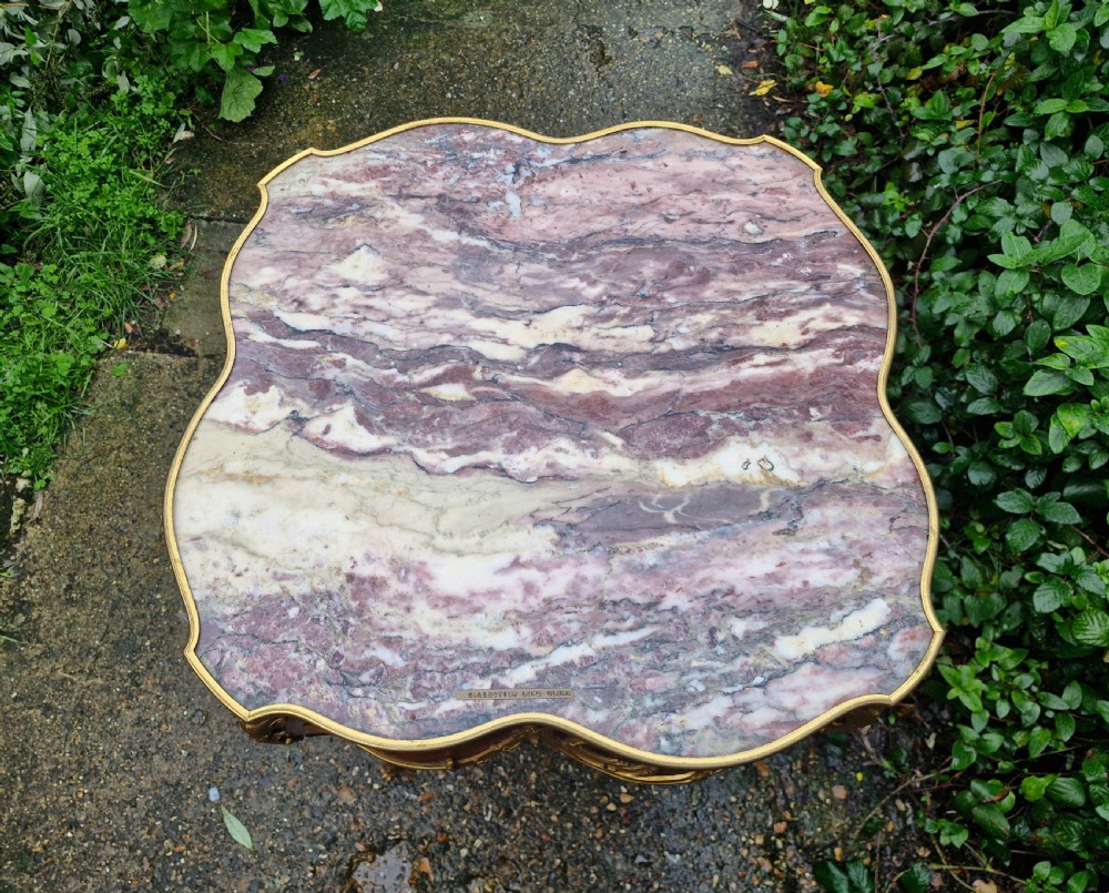 A French Louis XV style side table featuring a shaped variegated pink marble top, slender cabriole legs, and decorative gilt bronze mounts. View II