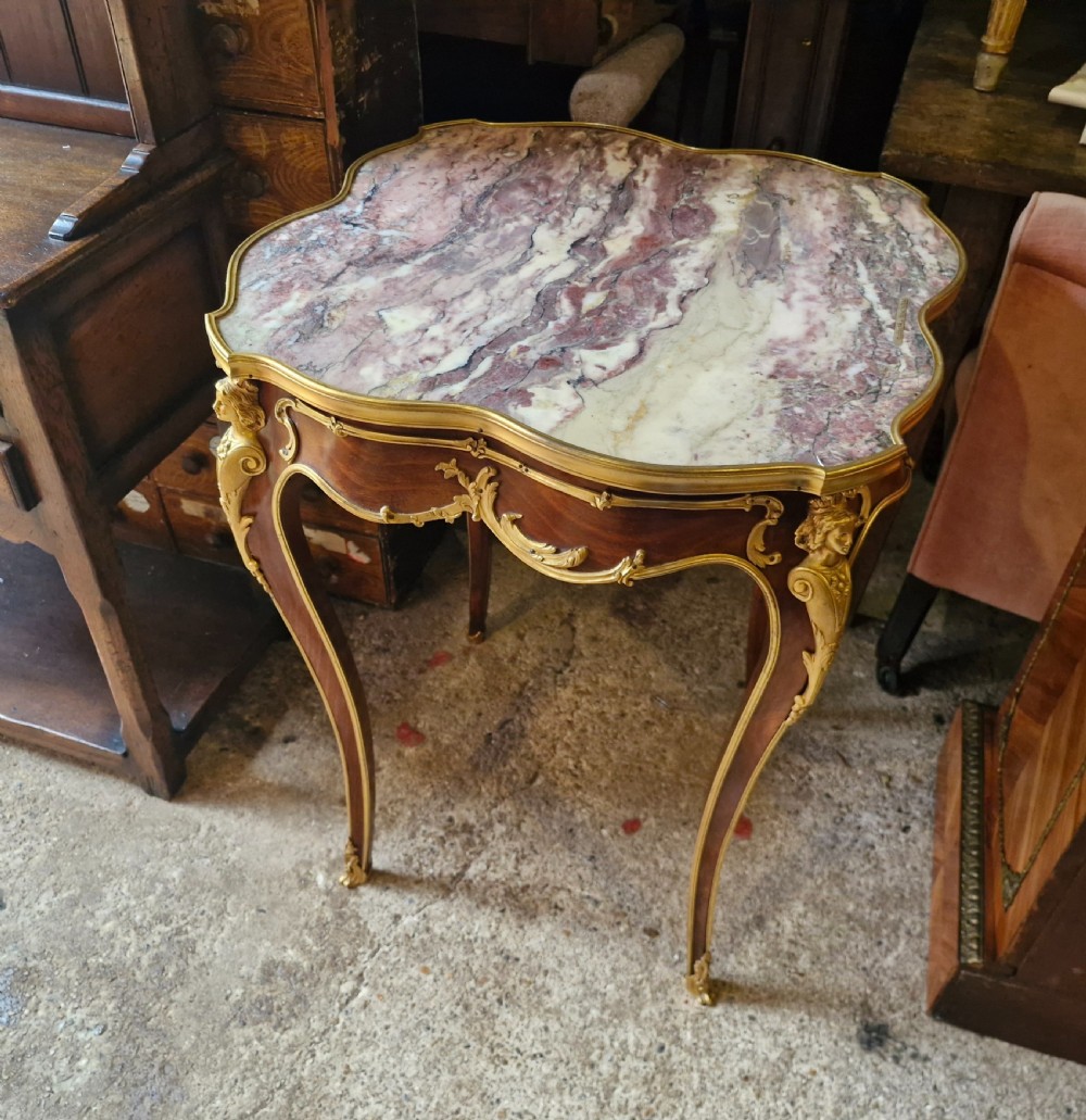 A French Louis XV style side table featuring a shaped variegated pink marble top, slender cabriole legs, and decorative gilt bronze mounts. View IV