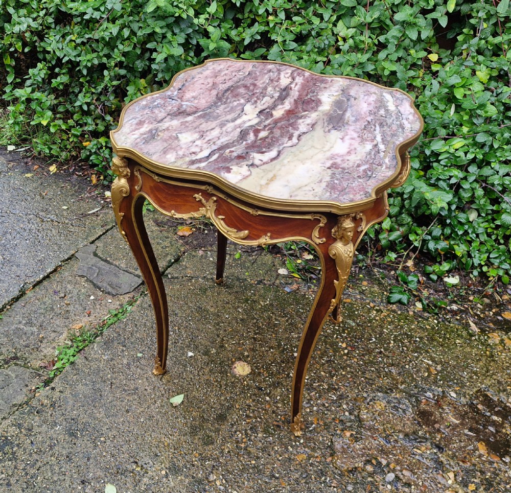 A French Louis XV style side table featuring a shaped variegated pink marble top, slender cabriole legs, and decorative gilt bronze mounts. View V