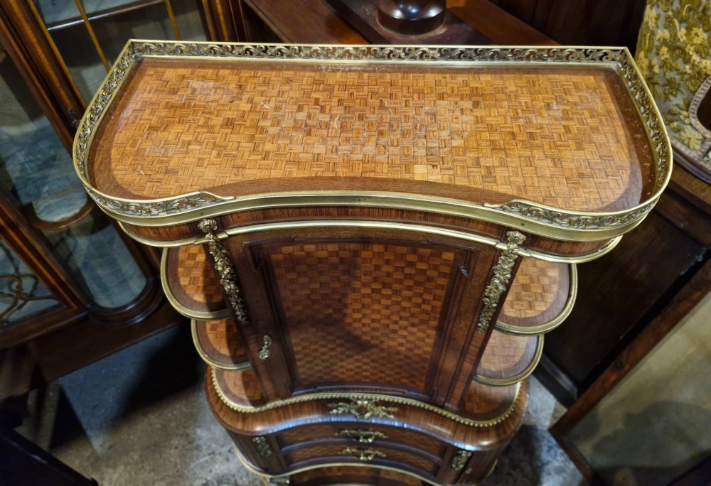 A French Louis XVI style tiered side cabinet crafted with checkerboard parquetry wood veneer, brass gallery, and ornamental ormolu mounts. View II