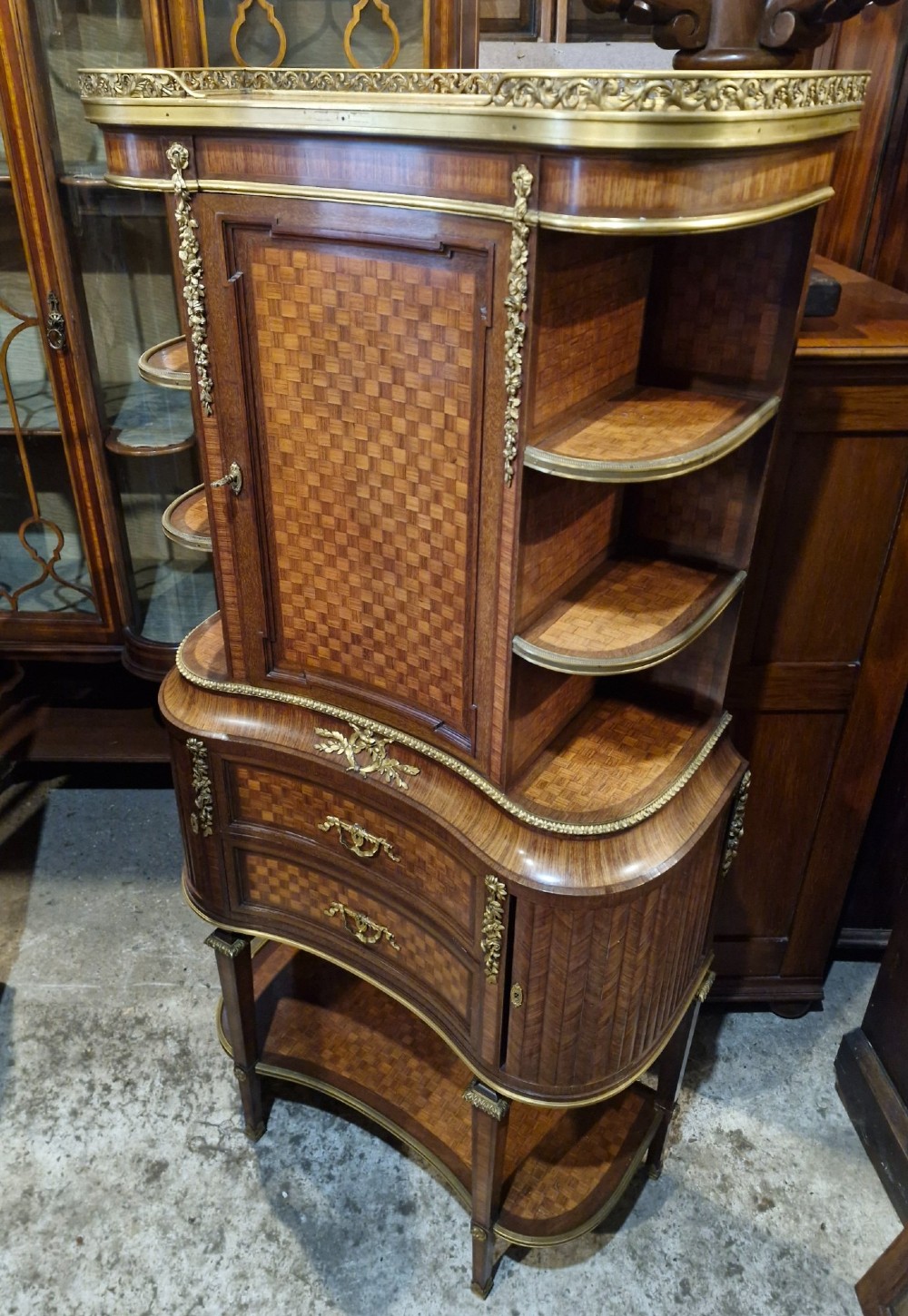A French Louis XVI style tiered side cabinet crafted with checkerboard parquetry wood veneer, brass gallery, and ornamental ormolu mounts. View III