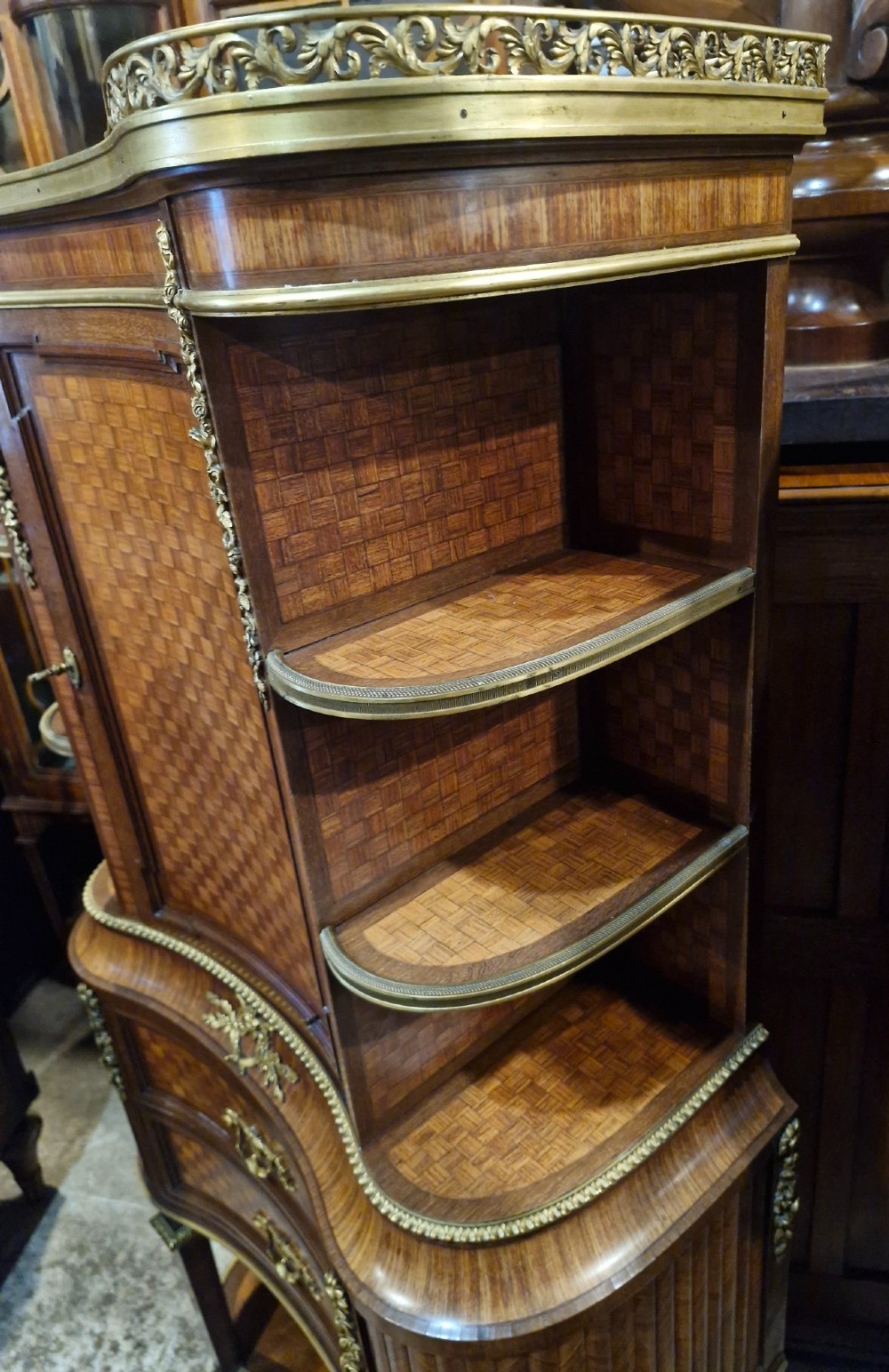 A French Louis XVI style tiered side cabinet crafted with checkerboard parquetry wood veneer, brass gallery, and ornamental ormolu mounts. View IV
