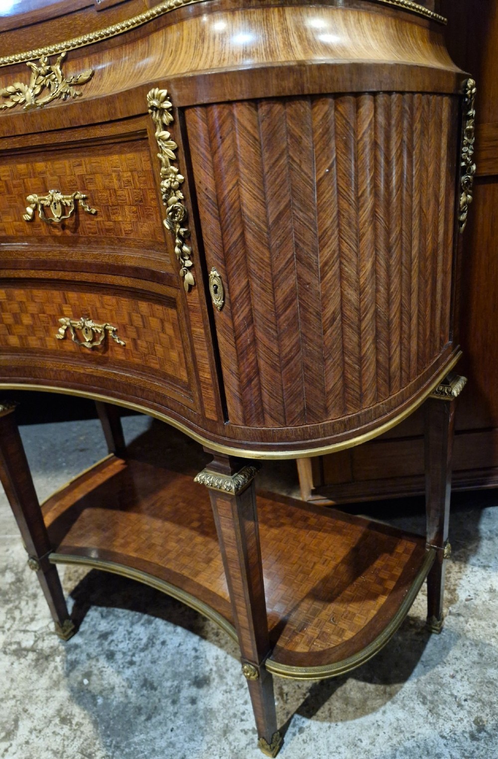 A French Louis XVI style tiered side cabinet crafted with checkerboard parquetry wood veneer, brass gallery, and ornamental ormolu mounts. View VI