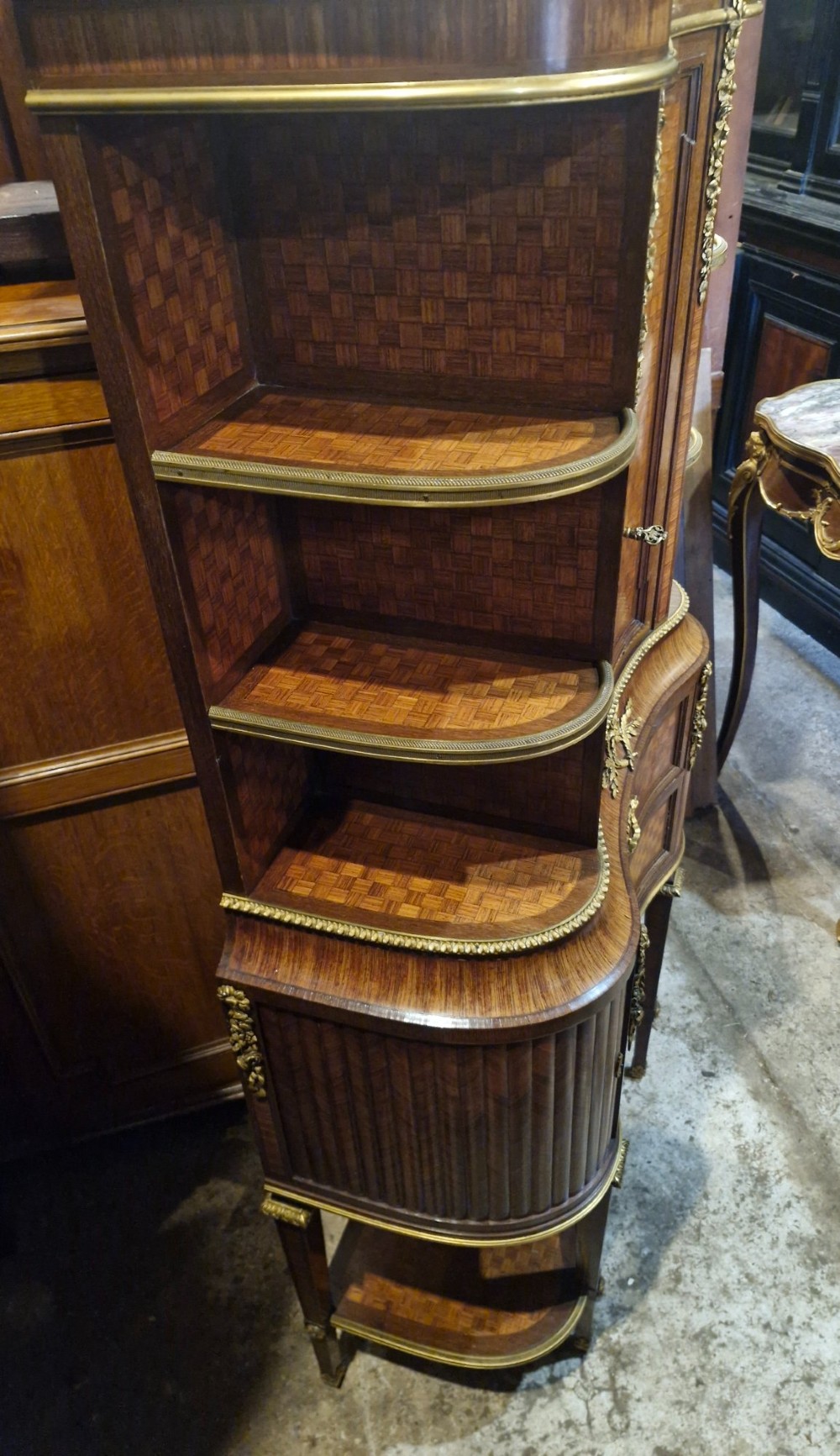 A French Louis XVI style tiered side cabinet crafted with checkerboard parquetry wood veneer, brass gallery, and ornamental ormolu mounts. View VIII