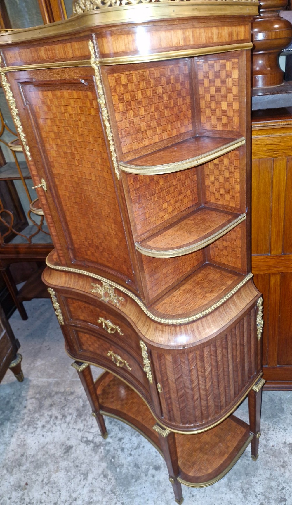 A French Louis XVI style tiered side cabinet crafted with checkerboard parquetry wood veneer, brass gallery, and ornamental ormolu mounts. View XII