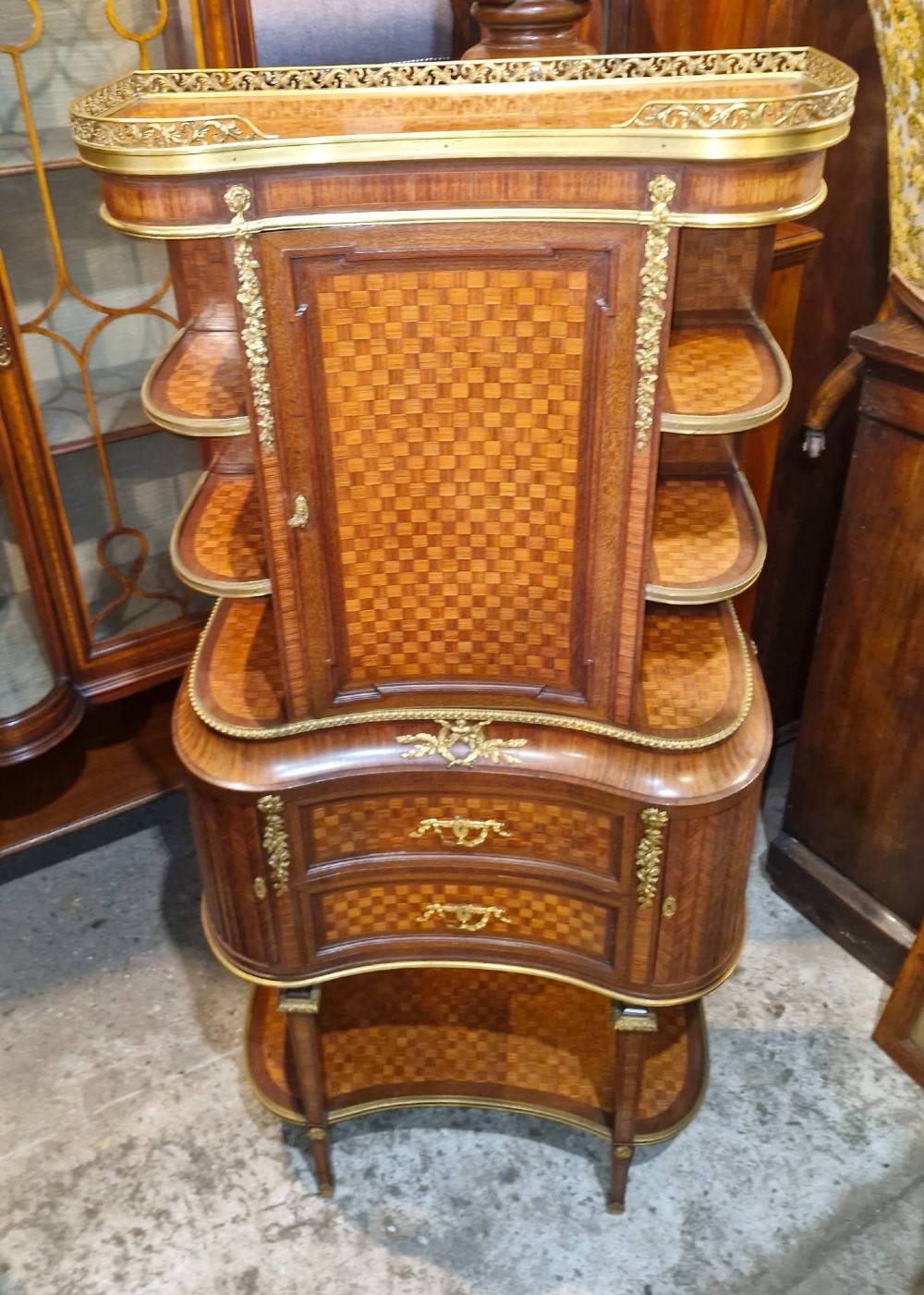 A French Louis XVI style tiered side cabinet crafted with checkerboard parquetry wood veneer, brass gallery, and ornamental ormolu mounts. View XIII