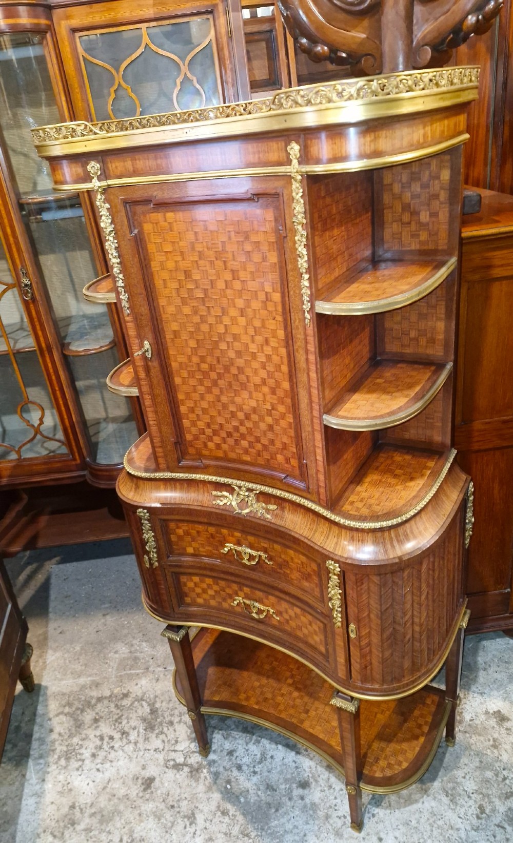 A French Louis XVI style tiered side cabinet crafted with checkerboard parquetry wood veneer, brass gallery, and ornamental ormolu mounts. View XV