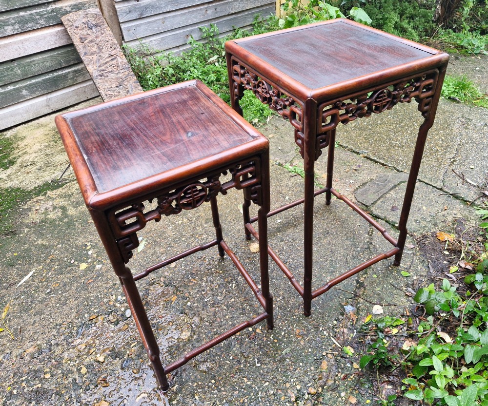 A pair of dark reddish-brown carved Chinese hardwood occasional tables of differing heights featuring bamboo-form legs and carved aprons with fretwork. View II
