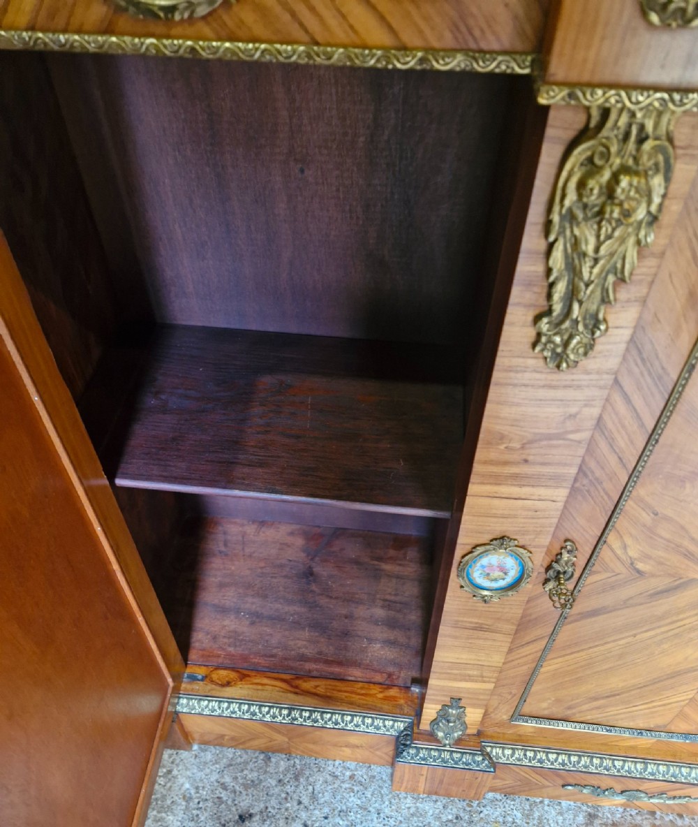 A 19th-century French parquetry side cabinet featuring three doors, brass mounts, and inset porcelain floral plaques. View V