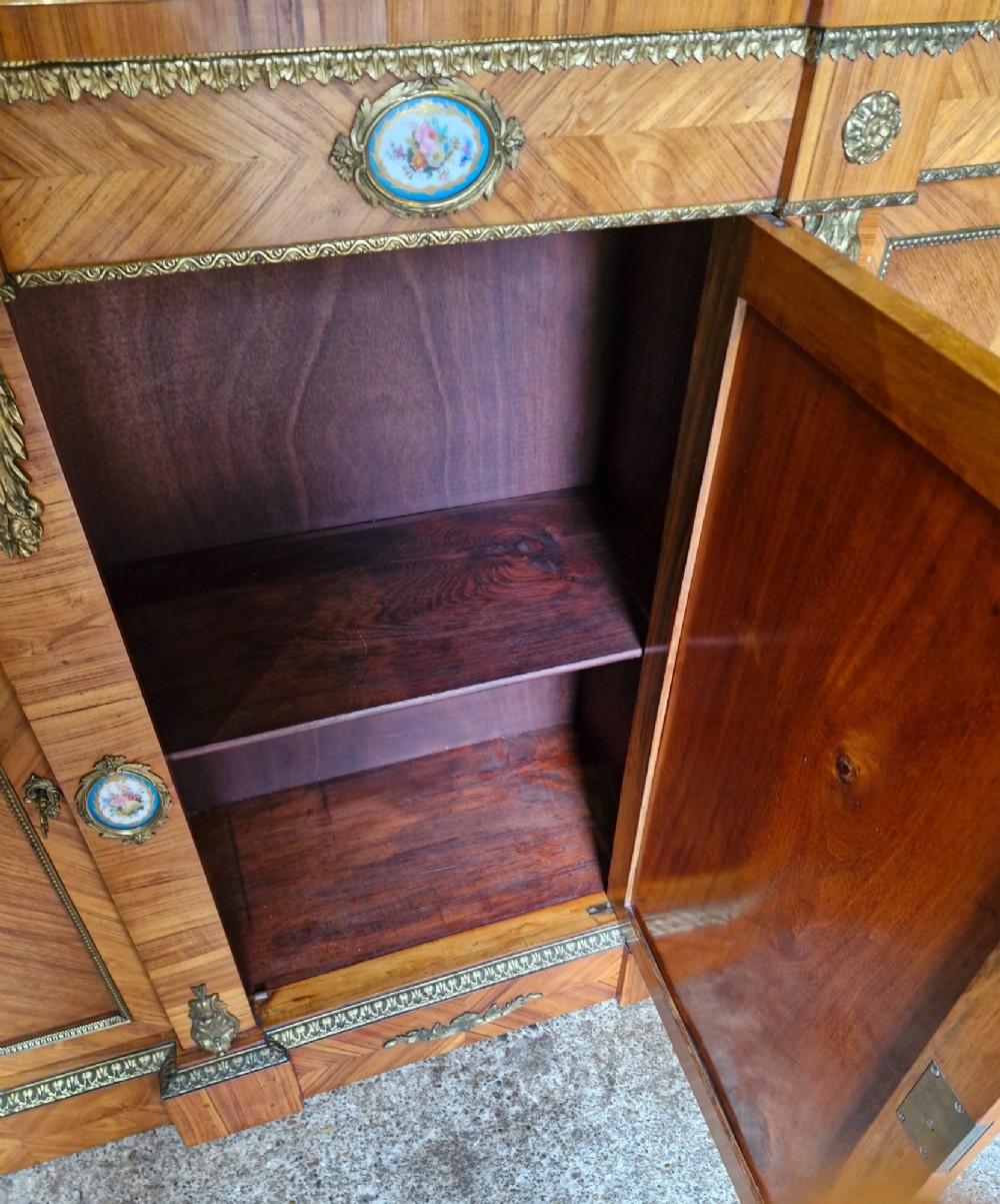 A 19th-century French parquetry side cabinet featuring three doors, brass mounts, and inset porcelain floral plaques. View VI