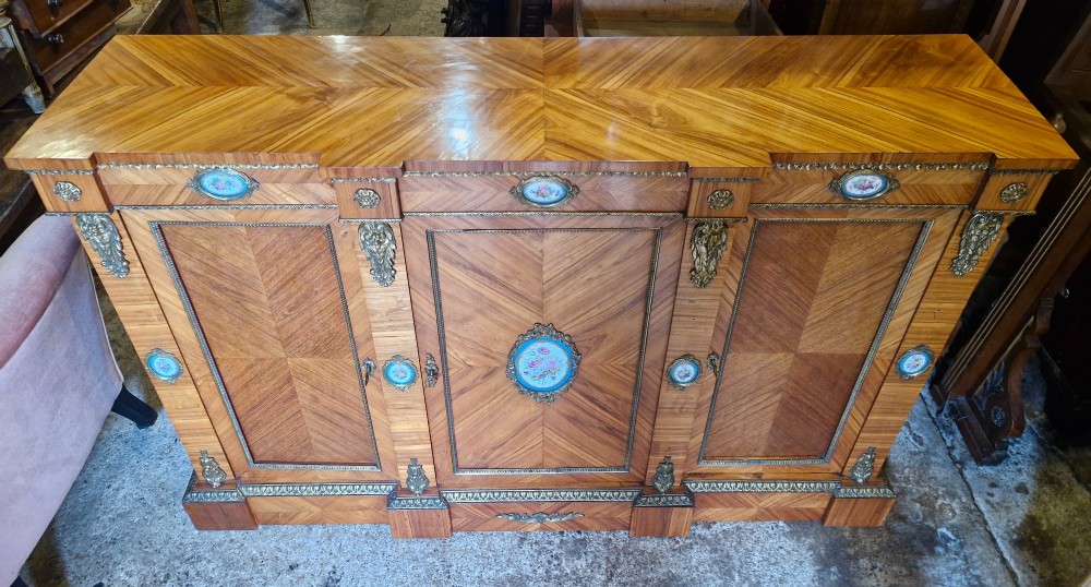 A 19th-century French parquetry side cabinet featuring three doors, brass mounts, and inset porcelain floral plaques. View VII