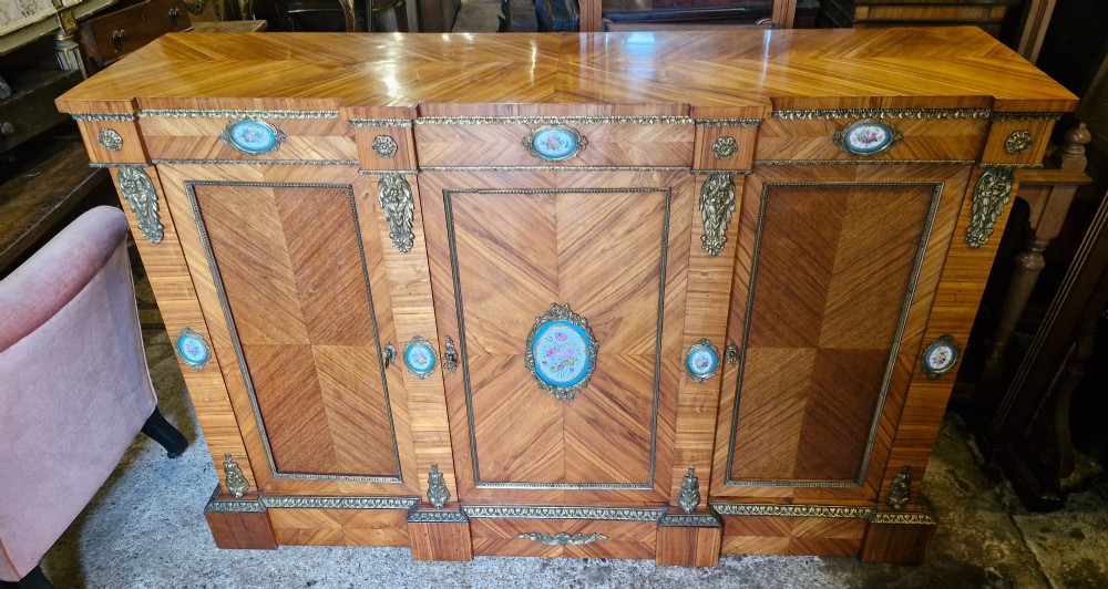 A 19th-century French parquetry side cabinet featuring three doors, brass mounts, and inset porcelain floral plaques. View VIII