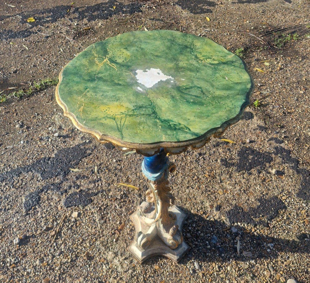 A carved and polychrome painted Italian Blackamoor pedestal stand featuring a figure in a blue top supporting a circular scalloped table top over a gilded scroll base. View VIII