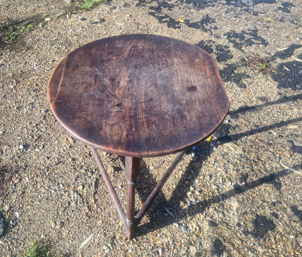 An early 19th-century dark oak cricket table featuring a circular top supported by three turned legs and a lower triangular stretcher. View III