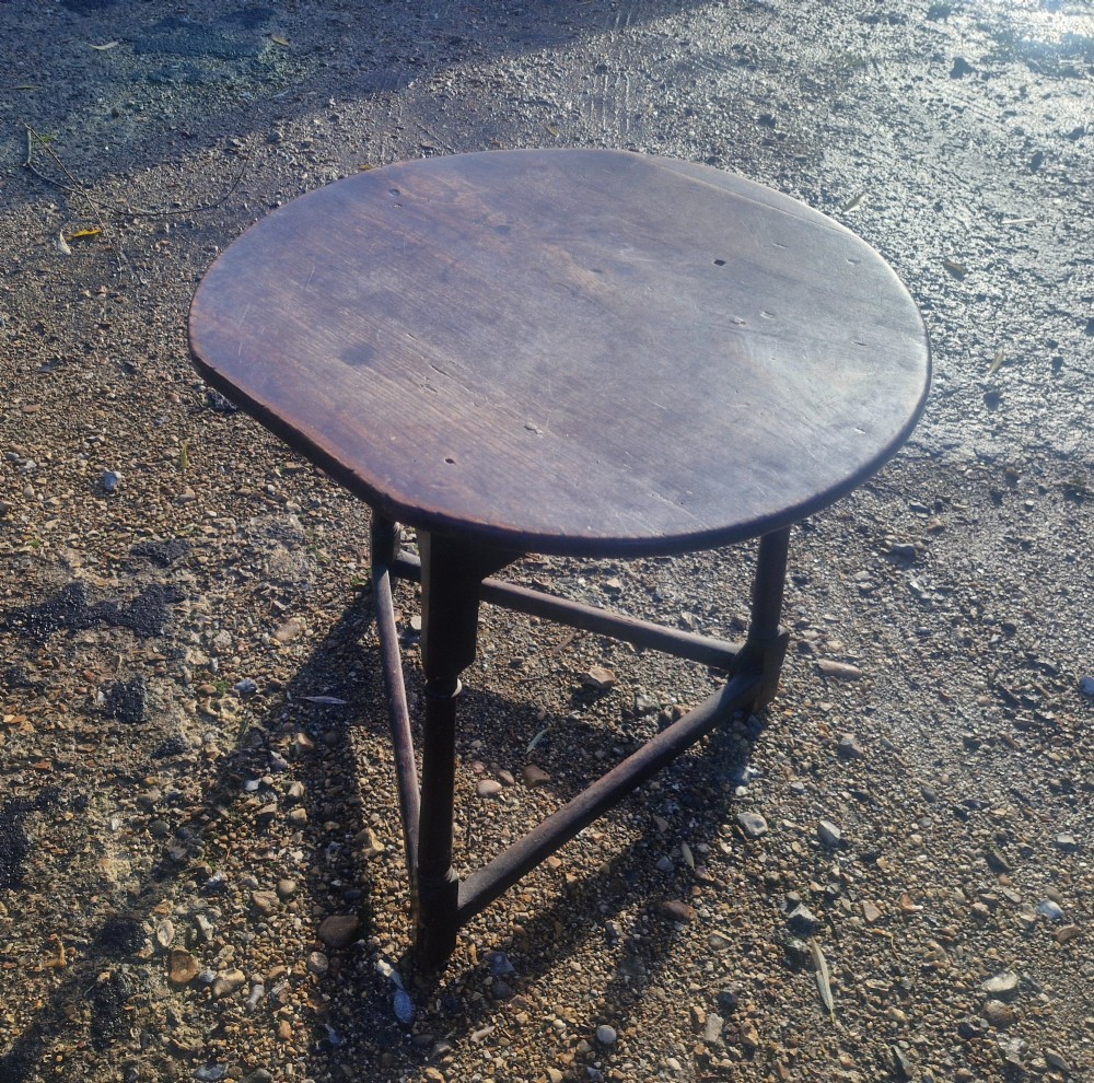 An early 19th-century dark oak cricket table featuring a circular top supported by three turned legs and a lower triangular stretcher. View V