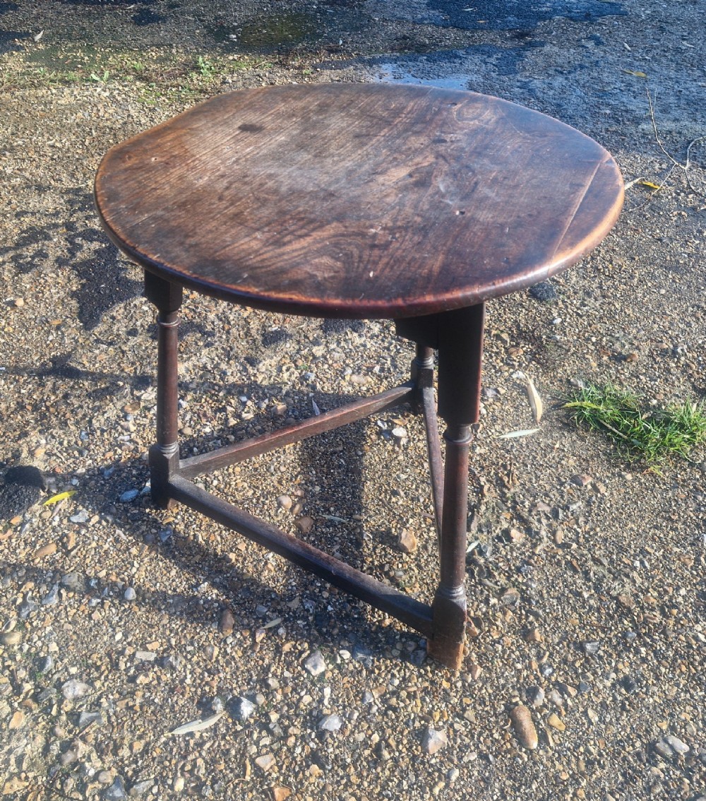 An early 19th-century dark oak cricket table featuring a circular top supported by three turned legs and a lower triangular stretcher. View IX