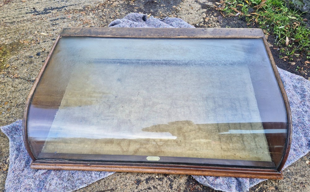 An antique dark oak tabletop display cabinet featuring a curved front glass pane and glazed top. View II