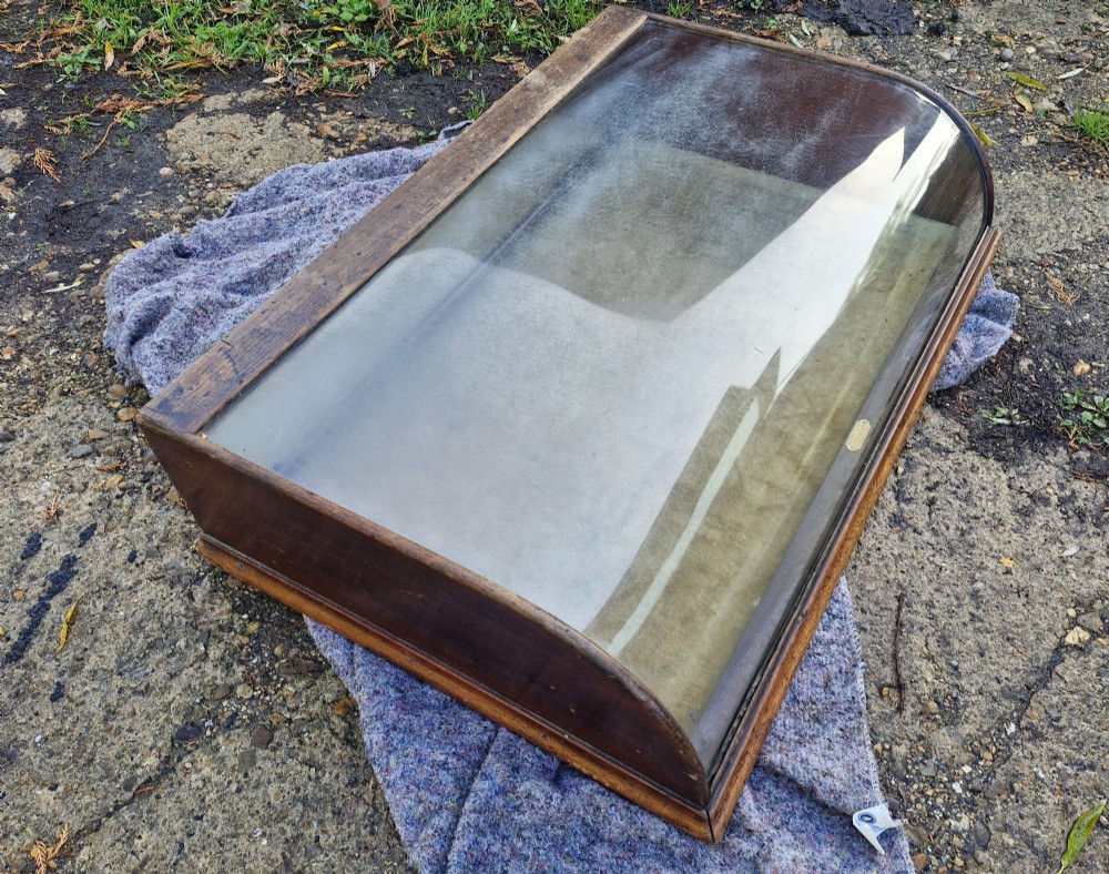An antique dark oak tabletop display cabinet featuring a curved front glass pane and glazed top. View VI
