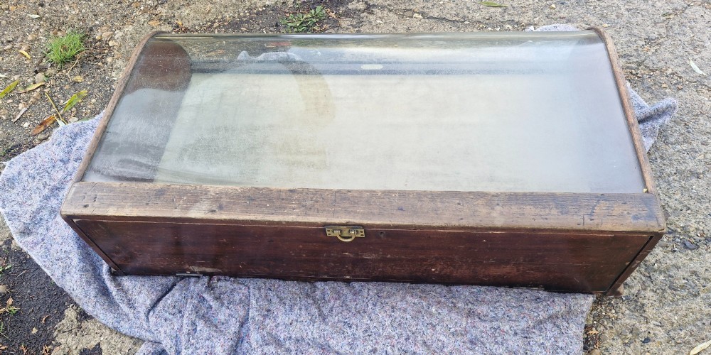 An antique dark oak tabletop display cabinet featuring a curved front glass pane and glazed top. View VIII