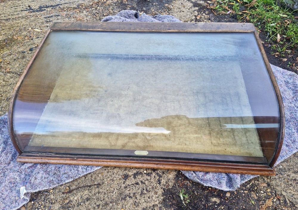 An antique dark oak tabletop display cabinet featuring a curved front glass pane and glazed top. View IX