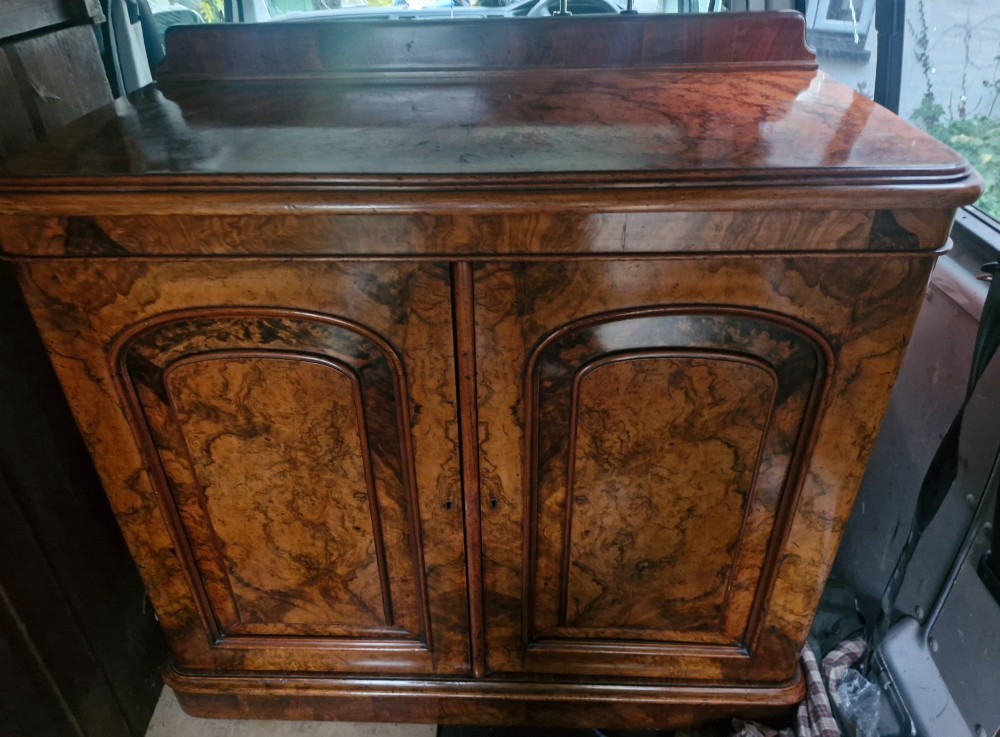 A Victorian burr walnut two-door side cabinet featuring rich natural wood grain figure, moulded arched panel doors, and a low rear upstand. View V