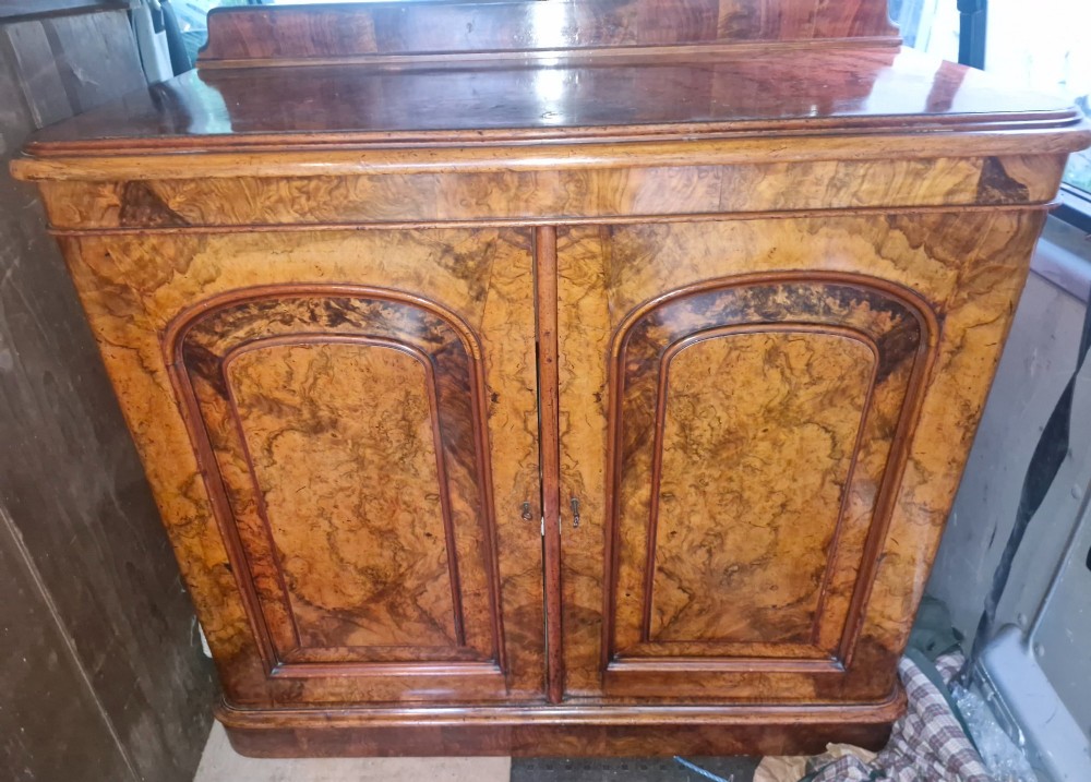 A Victorian burr walnut two-door side cabinet featuring rich natural wood grain figure, moulded arched panel doors, and a low rear upstand. View VI