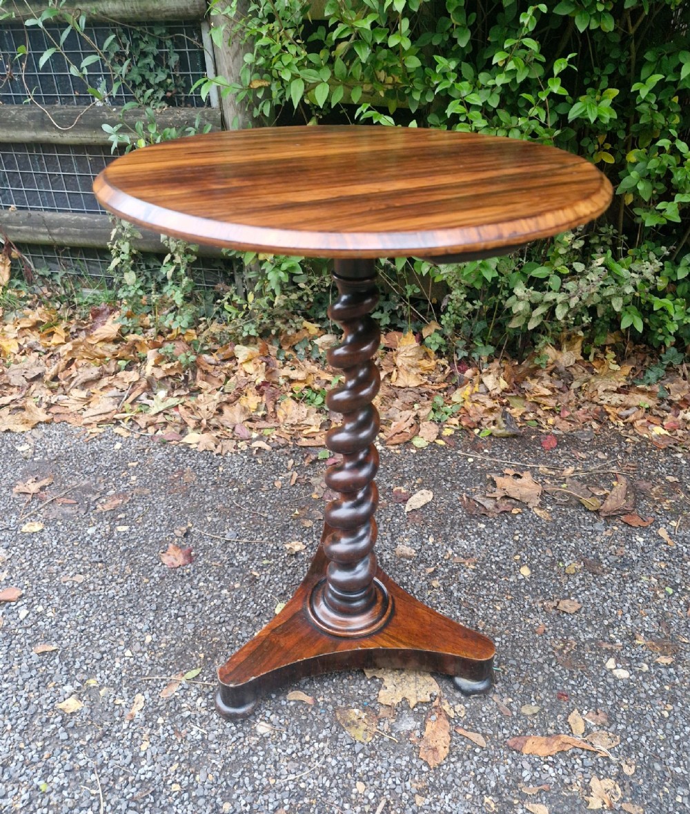 A circular mid-Victorian rosewood occasional table featuring a figured wood top, a carved spiral barley-twist central stem, and a triform platform base. View V