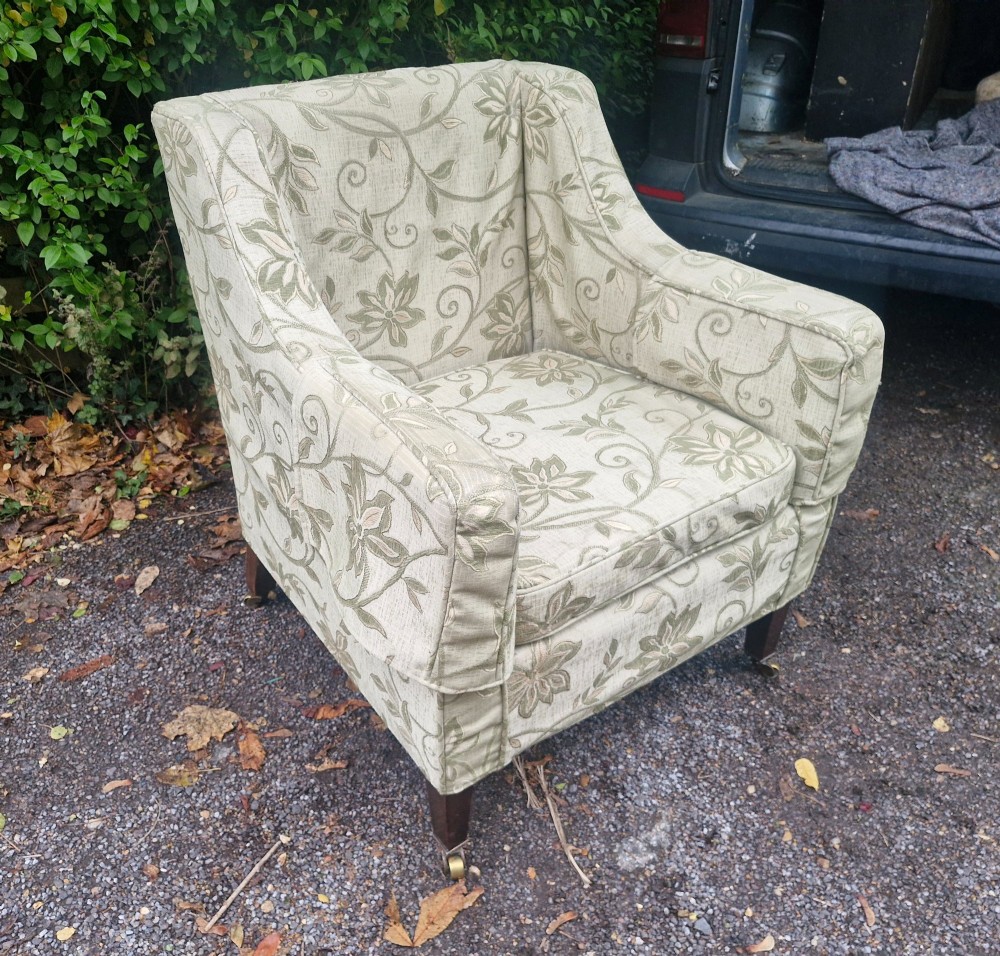 An Edwardian armchair upholstered in patterned green damask fabric with matching braided trim, supported on square tapered mahogany legs with brass castors. View III