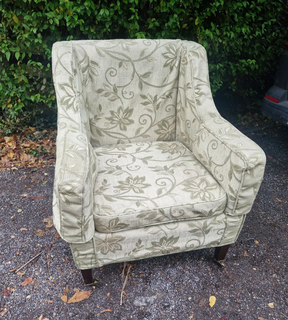 An Edwardian armchair upholstered in patterned green damask fabric with matching braided trim, supported on square tapered mahogany legs with brass castors. View VII