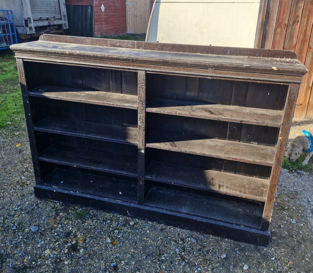 A low late Victorian open double-bay pine bookcase featuring a dark painted distressed finish, fixed horizontal shelving, and a plinth base. View II