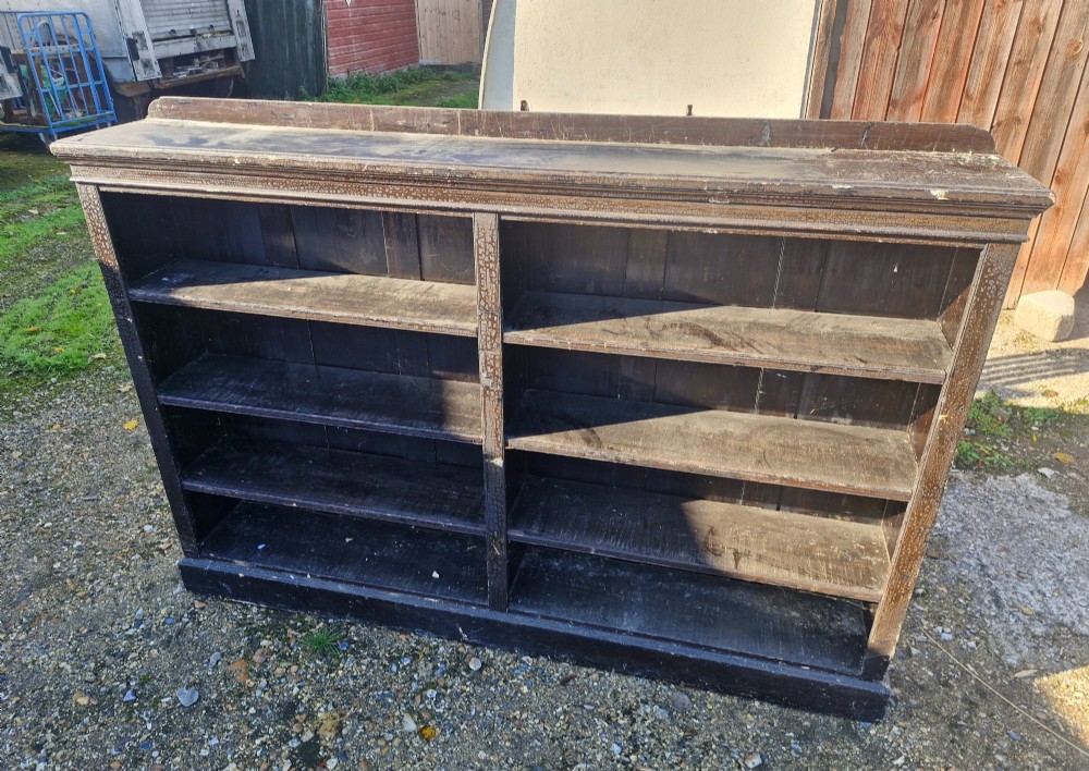A low late Victorian open double-bay pine bookcase featuring a dark painted distressed finish, fixed horizontal shelving, and a plinth base. View IV