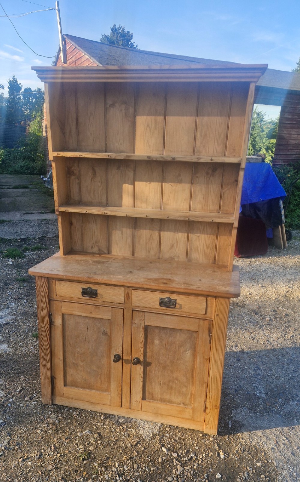 An early 20th-century natural pine kitchen dresser featuring a three-tier open shelf rack over two drawers and a two-door cabinet base.